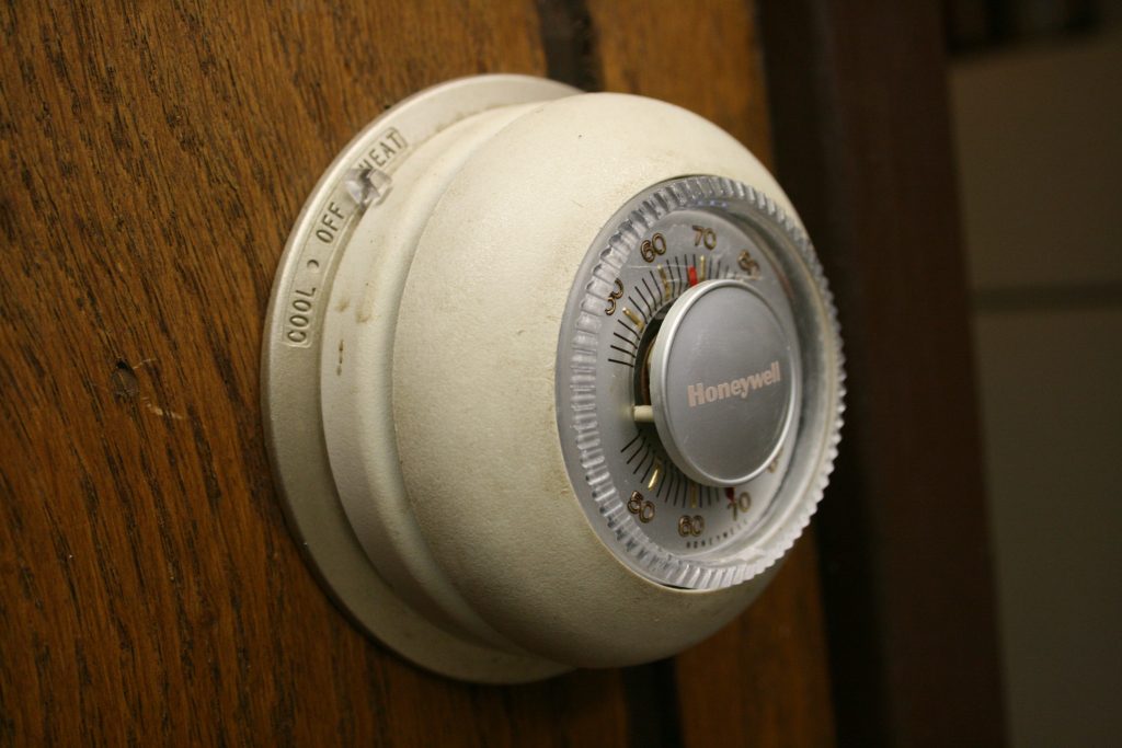 Older installed Honeywell T87 Round thermostat on a wood wall, illustrating the Round family
