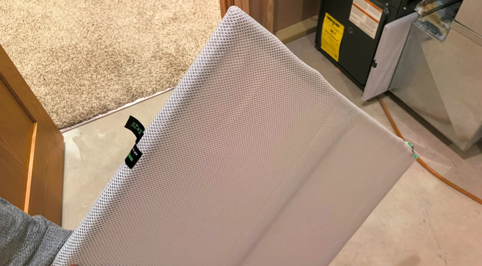 Rectangular HVAC filter held beside heating and cooling equipment