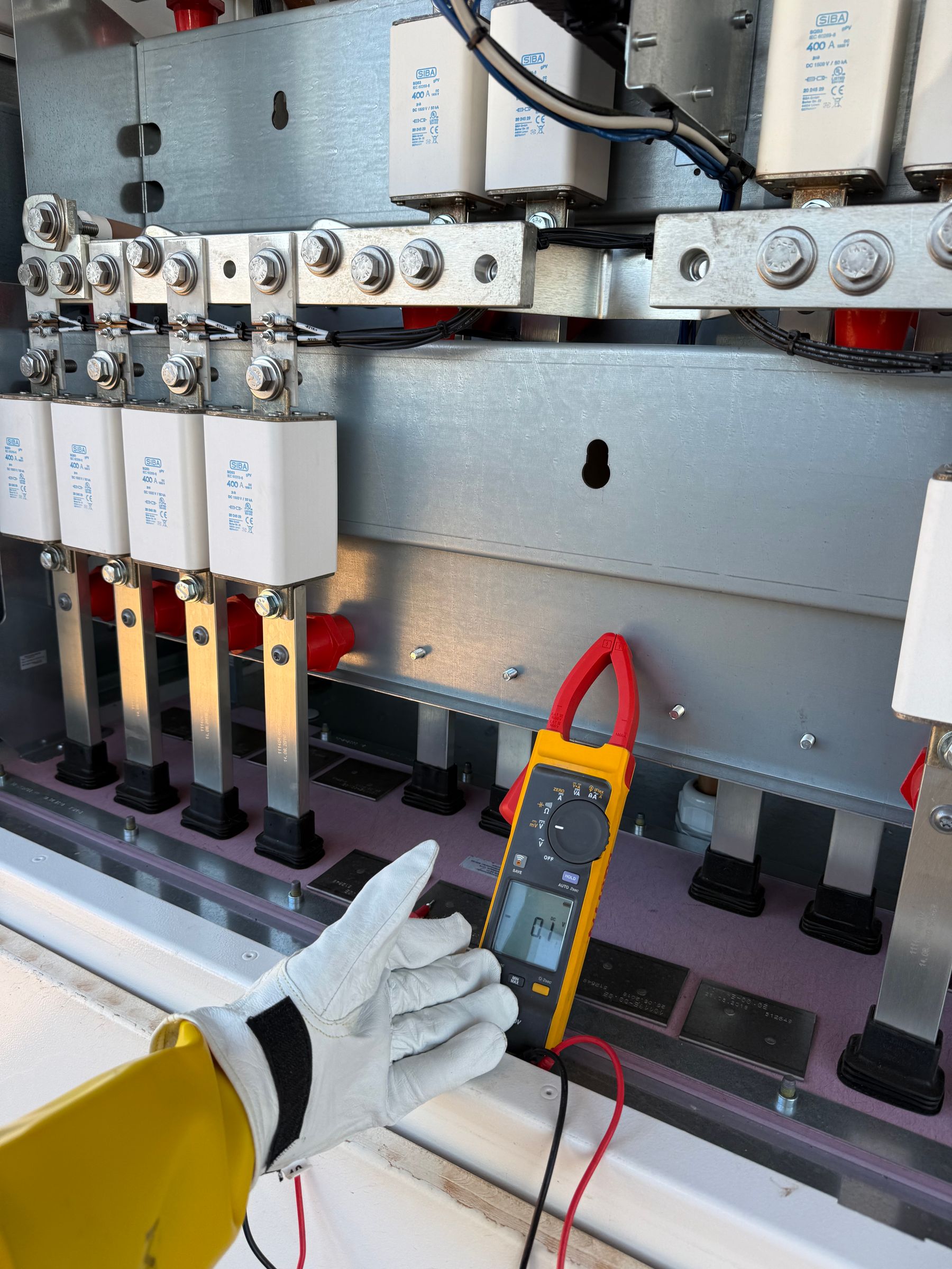 Gloved hand and meter at electrical panel