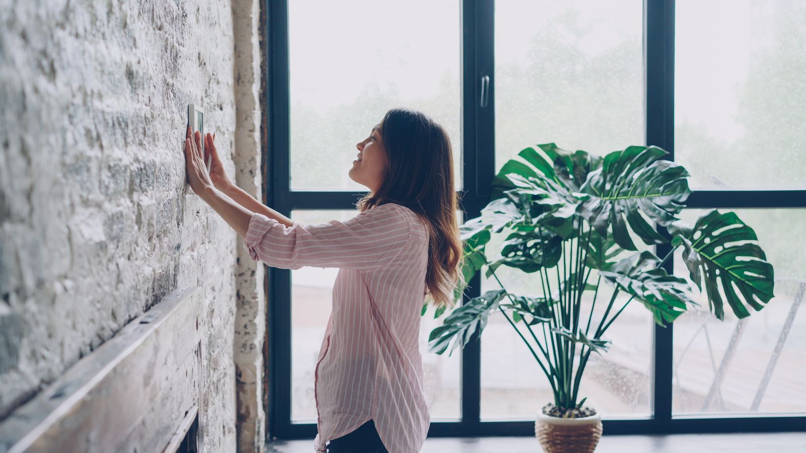Person adjusting a wall-mounted thermostat